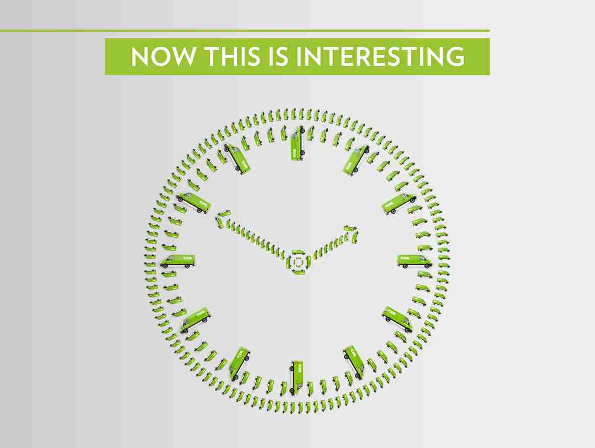 A clock made of green toy buses with the text "Now This Is Interesting" above it on a light gray background.